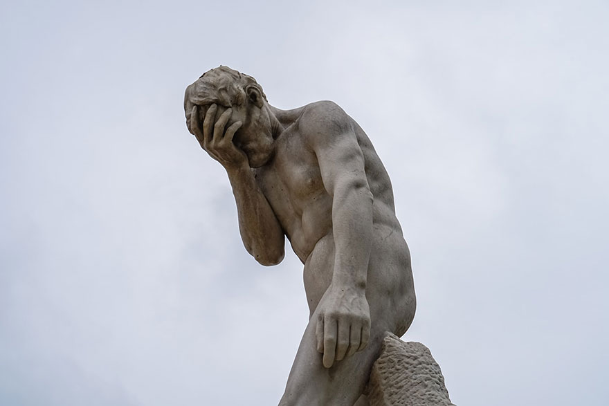 a statue with a facepalm gesture