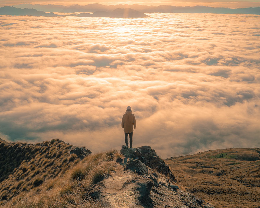 man on top of a mountain overlooking a sea of clouds