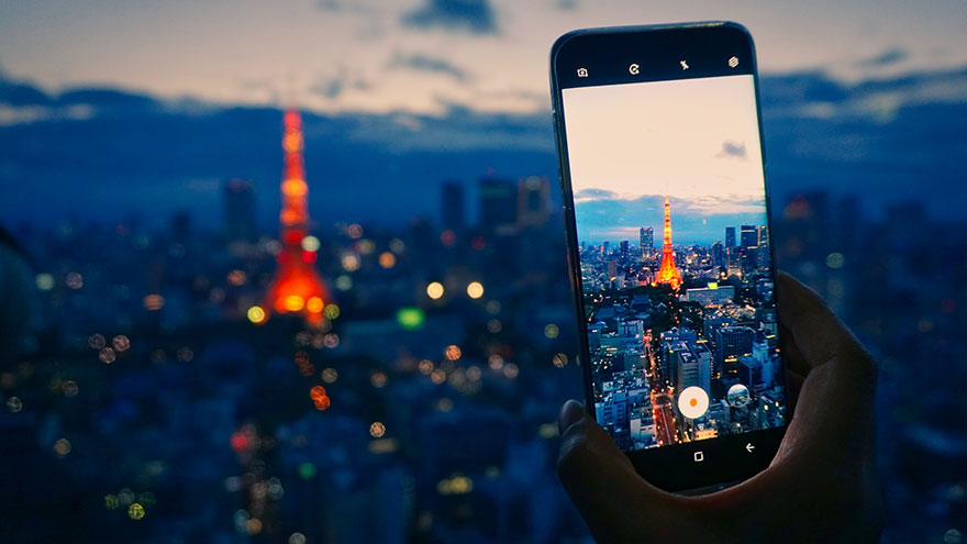 person taking a nightshot photo of a city using a mobile phone