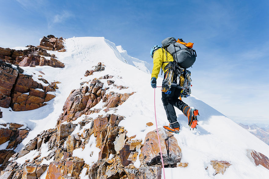Mountaineer climbing a snow capped mountain with full gear