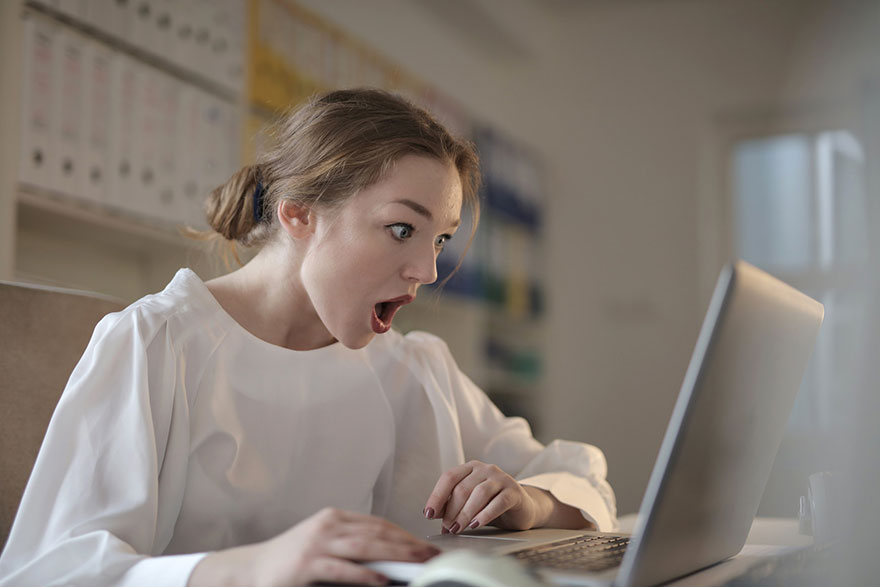 a person who looks shocked while looking at her laptop