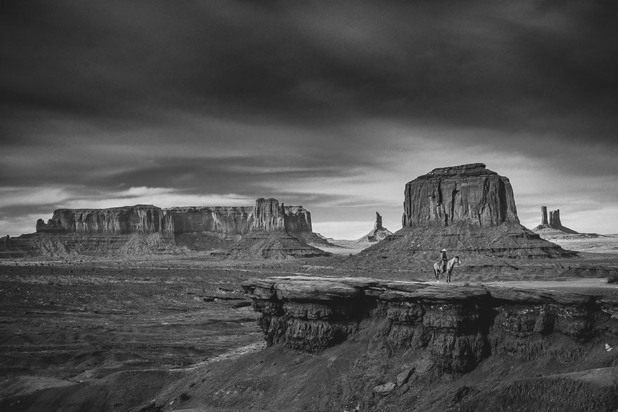 a lone cowboy on his horse on top of a cliffin the grand canyon