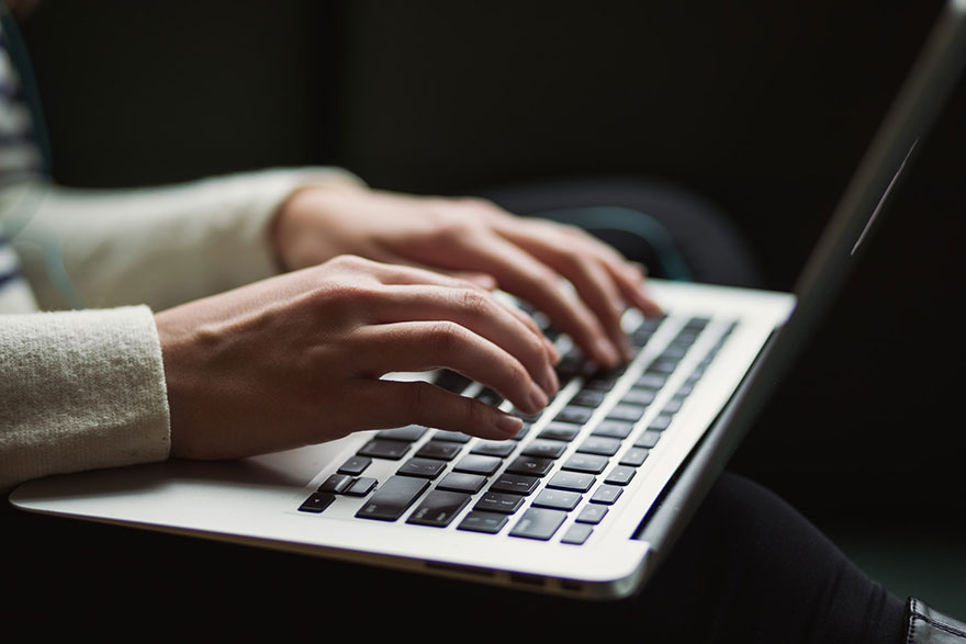 both hands typing on a laptop