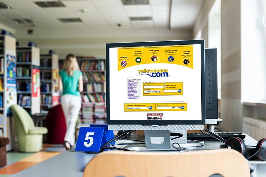 Image inside a library with a big computer screen showing yellowpages.com