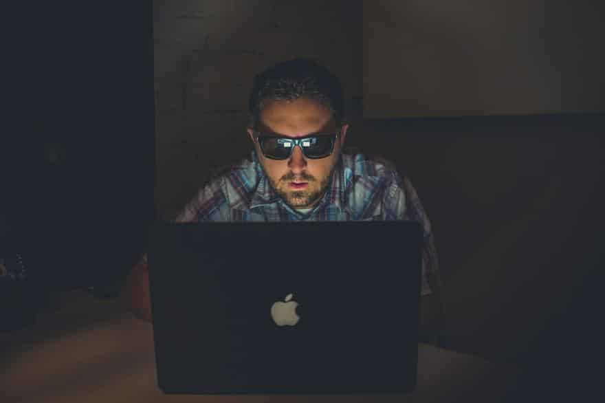 Shady man wearing sunglasses in front of a laptop