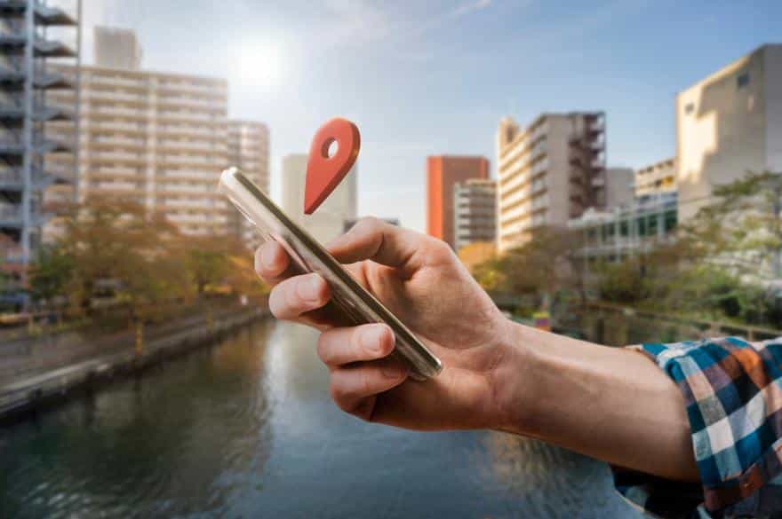 Close-up of a hand holding a phone with a location pin above it