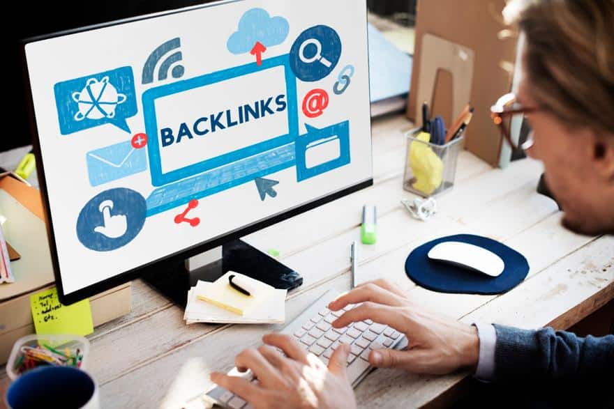 Man working on a desktop with the word Backlinks on the monitor